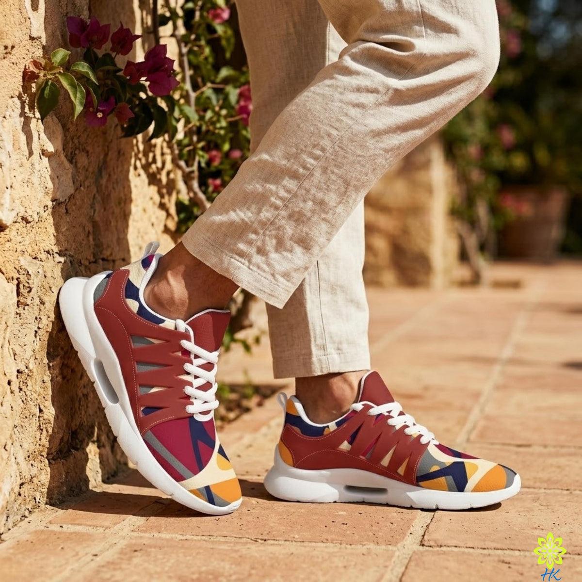 A person wearing colorful sneakers is standing against a stone wall with flowers.