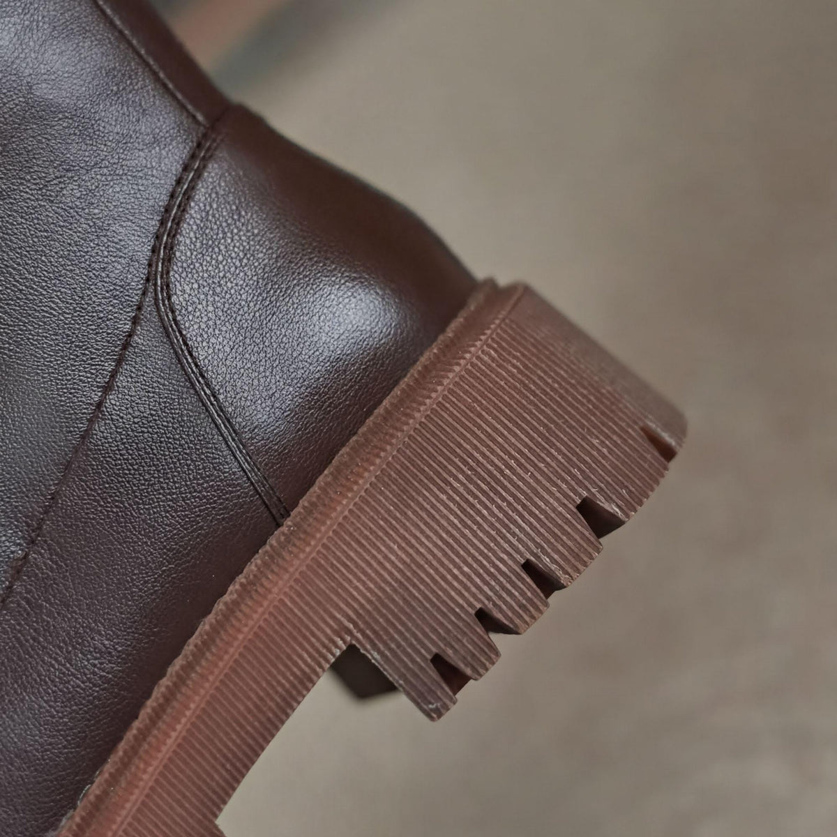 A close-up view of the sole of a brown leather boot, showing the tread pattern and sole material.