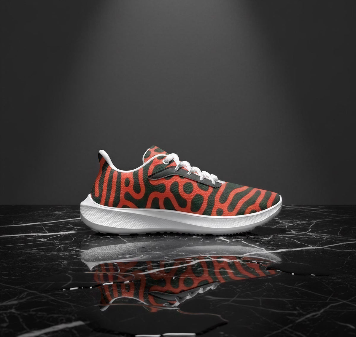 A single sneaker with a bold, abstract pattern in orange and black colors is displayed on a black marble surface, reflecting the shoe and the background.
