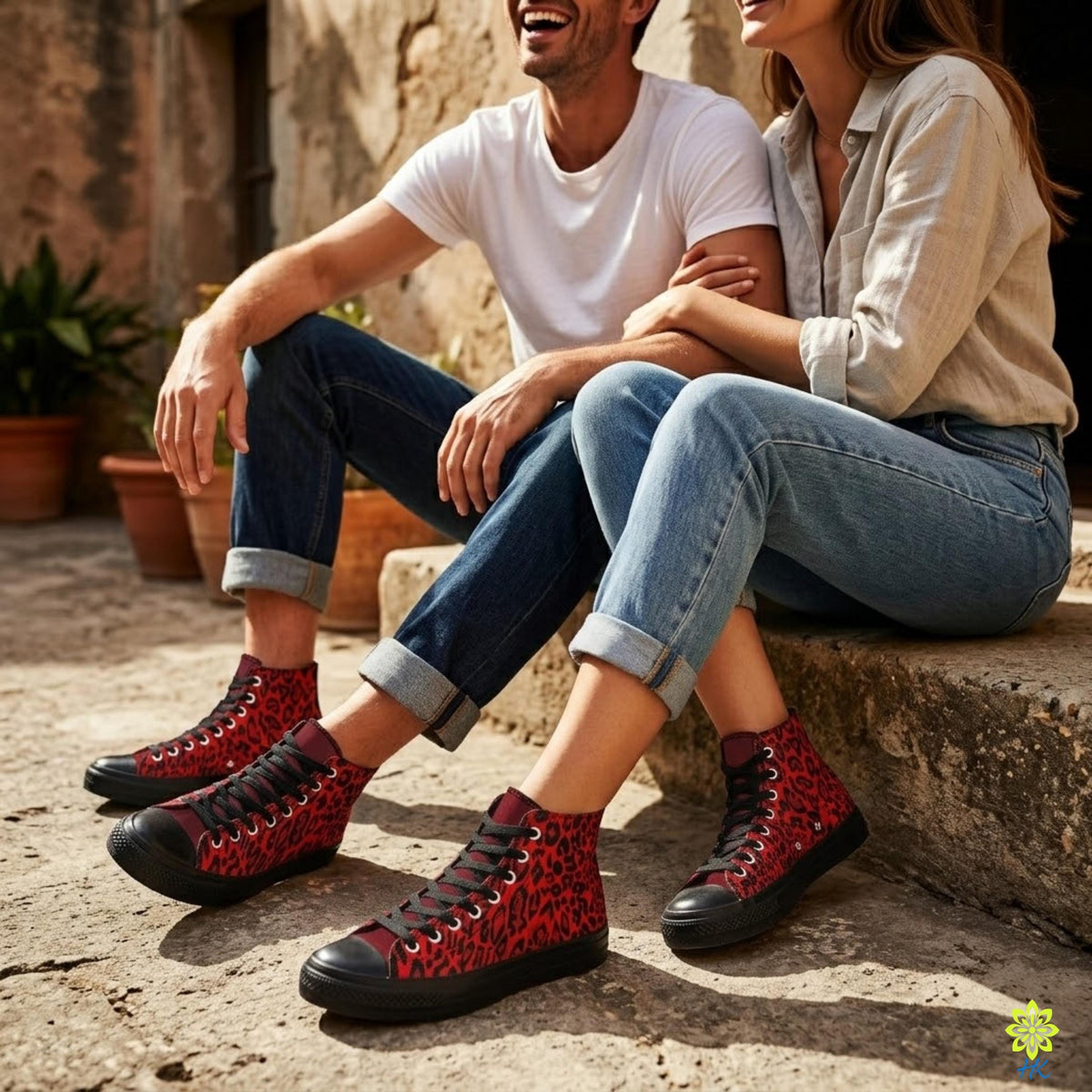 A man and a woman sitting on a stone step, smiling and wearing red and black high-top sneakers.