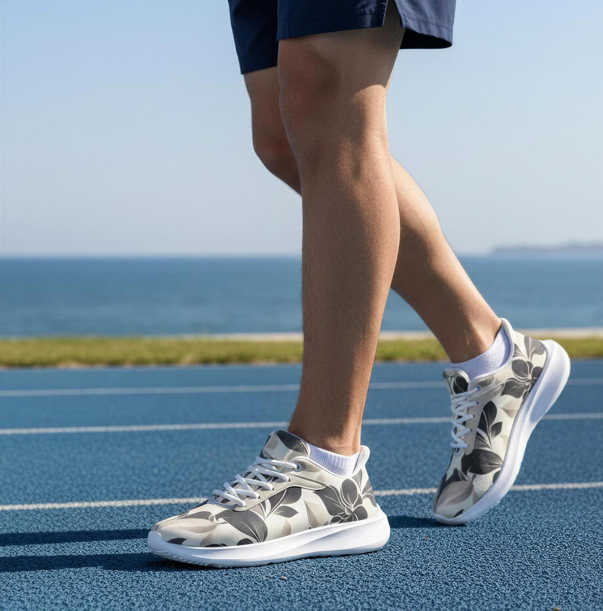 A person wearing patterned sneakers is walking on a blue track near the ocean.