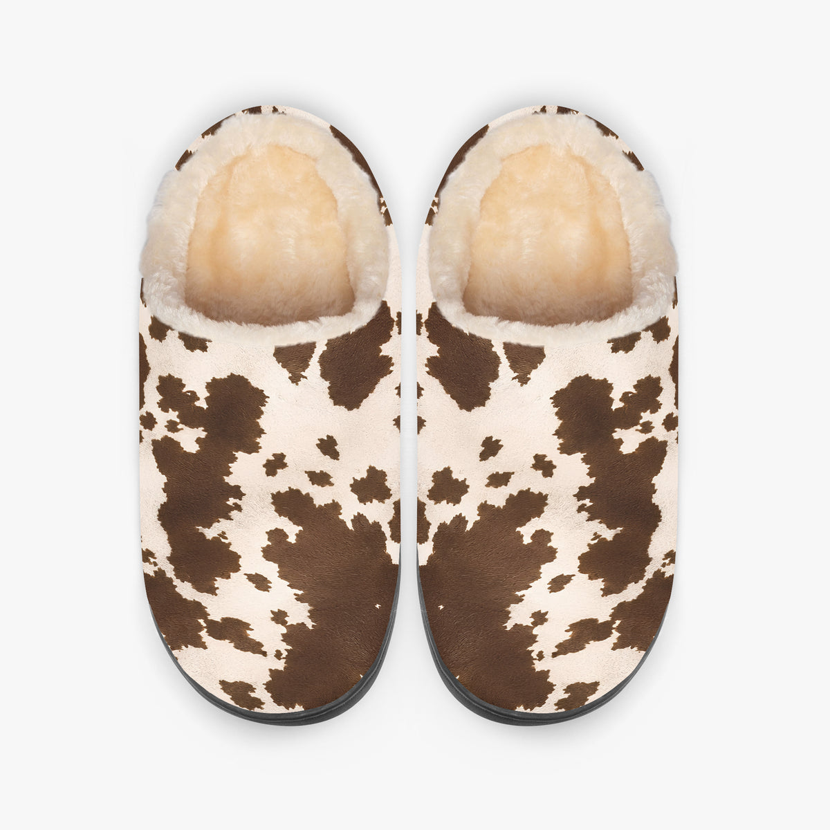 Vista cenital de un par de zapatillas de casa de vaca que muestra el estampado superior y el forro crema mullido