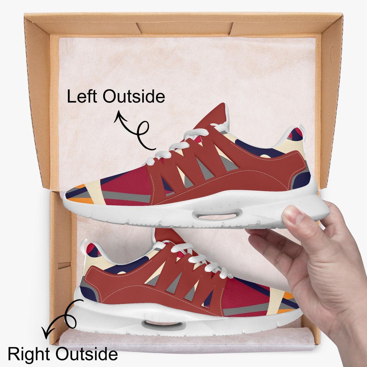 A hand is holding a pair of red and white sneakers, with the left shoe positioned outside the box and the right shoe inside the box.
