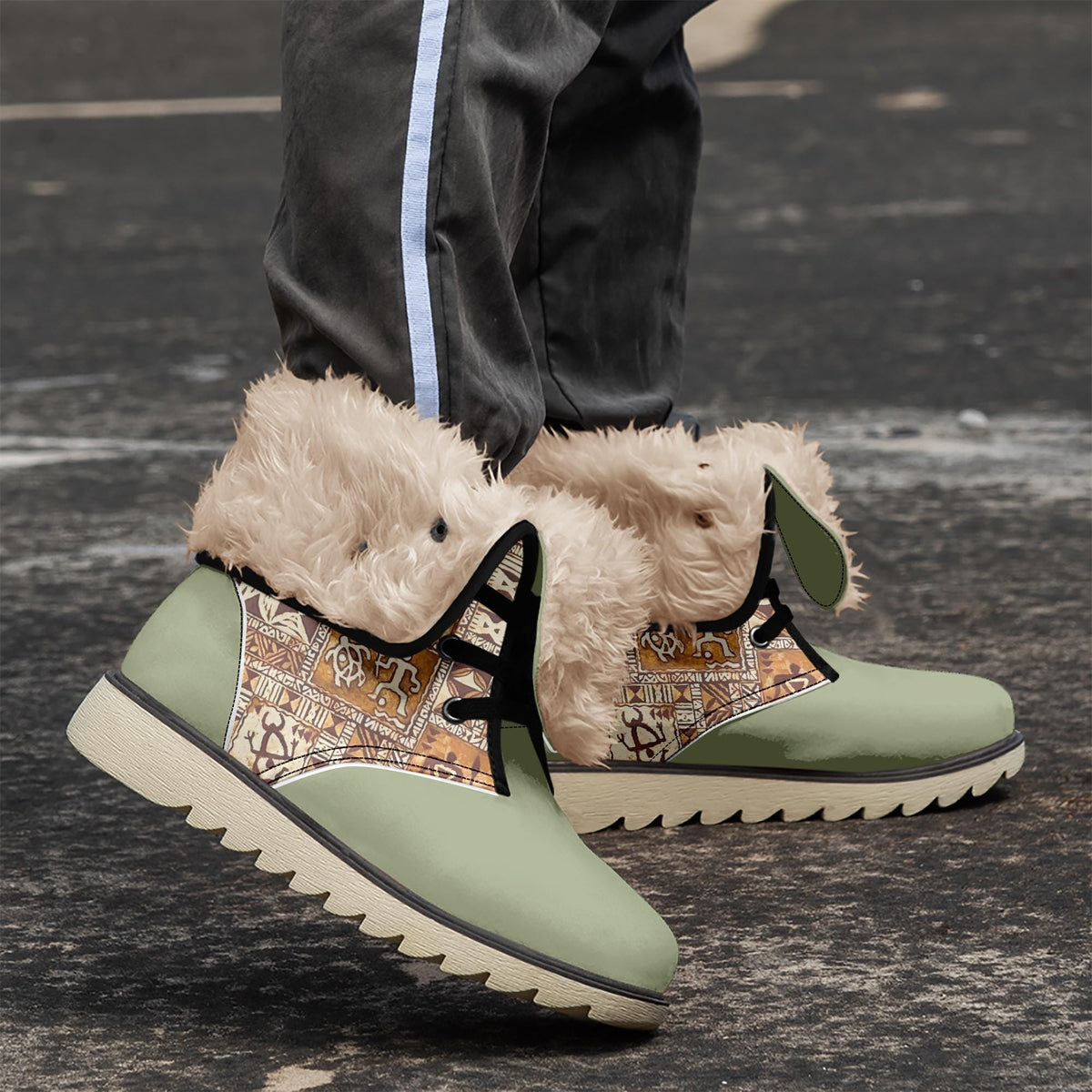 A pair of green and white boots with fur trim, worn by a person standing on a paved surface.
