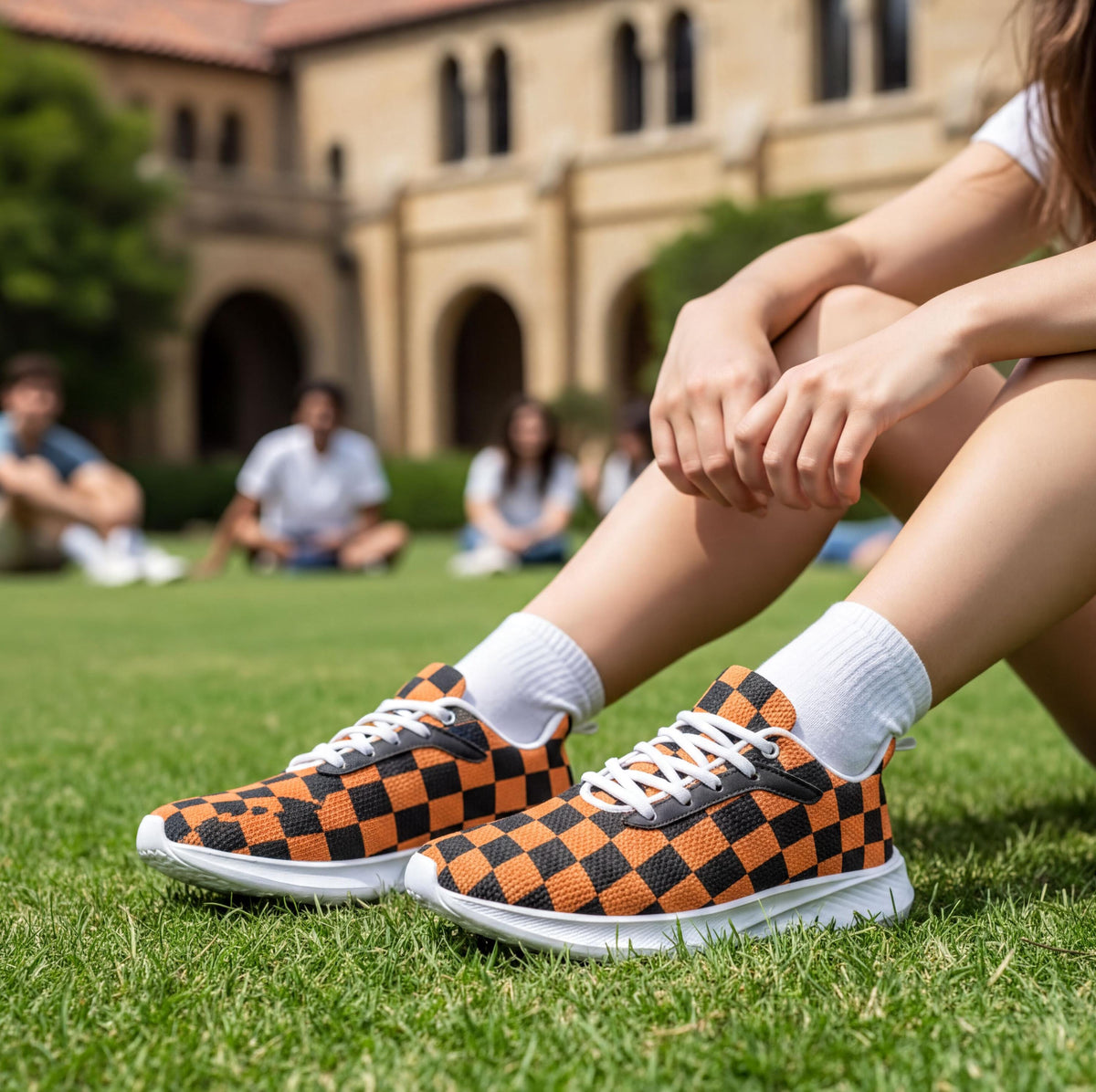 A person sitting on the grass wearing orange and black checkered sneakers.
