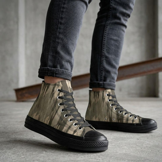 A person wearing camouflage-patterned high-top sneakers and black jeans stands in an indoor setting.