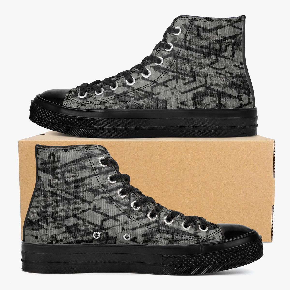 A pair of black and gray patterned high-top sneakers placed on top of a cardboard box.