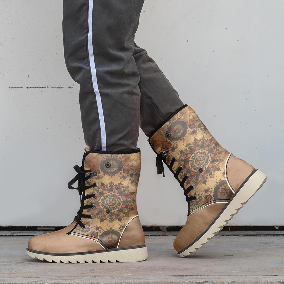 A person wearing tan and black patterned boots stands against a white wall.