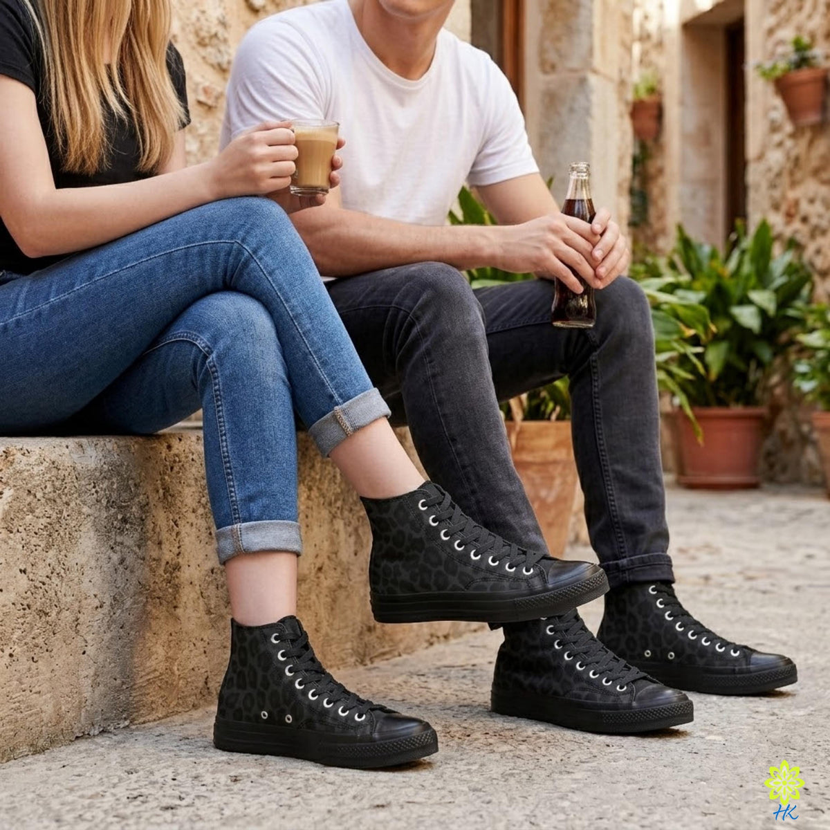 A man and a woman are sitting on a stone wall, enjoying a drink and each other's company.