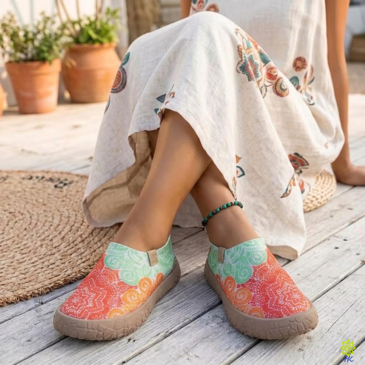 Profilo laterale di scarpe slip-on a mandala indossate con un abito di lino stampato su una terrazza in legno