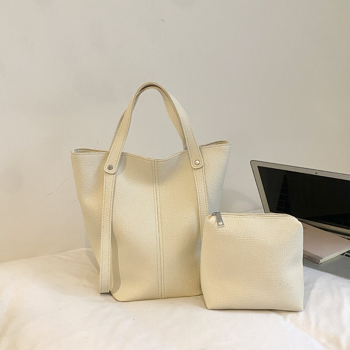 Beige white tote bag and clutch set displayed on a marble surface