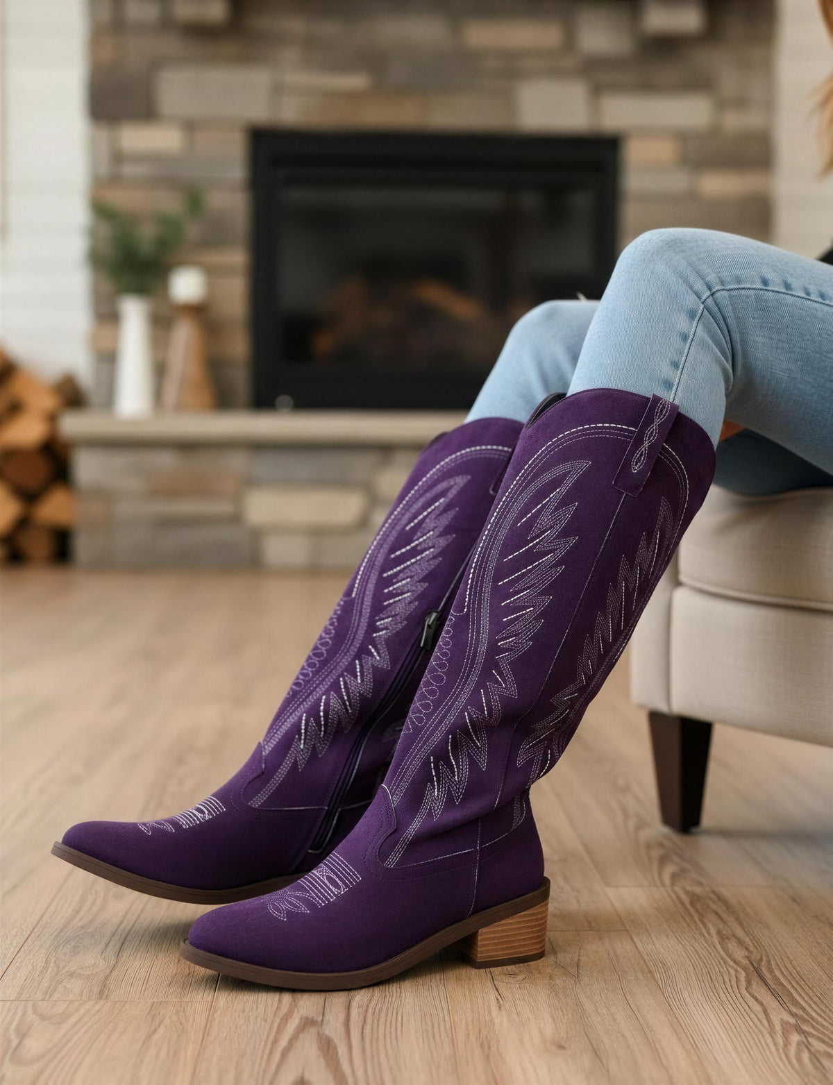 A person is sitting on a chair in a room with a fireplace in the background. The person is wearing purple cowboy boots.