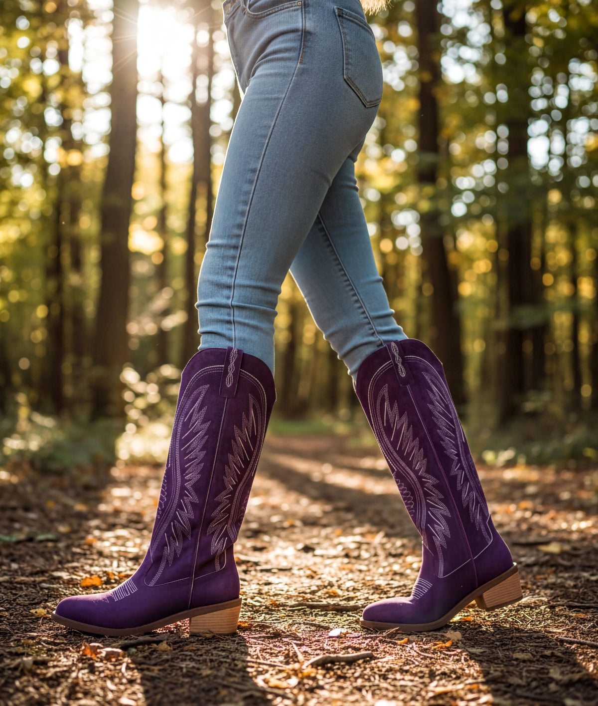 A person wearing purple cowboy boots is walking on a dirt path through a forest.