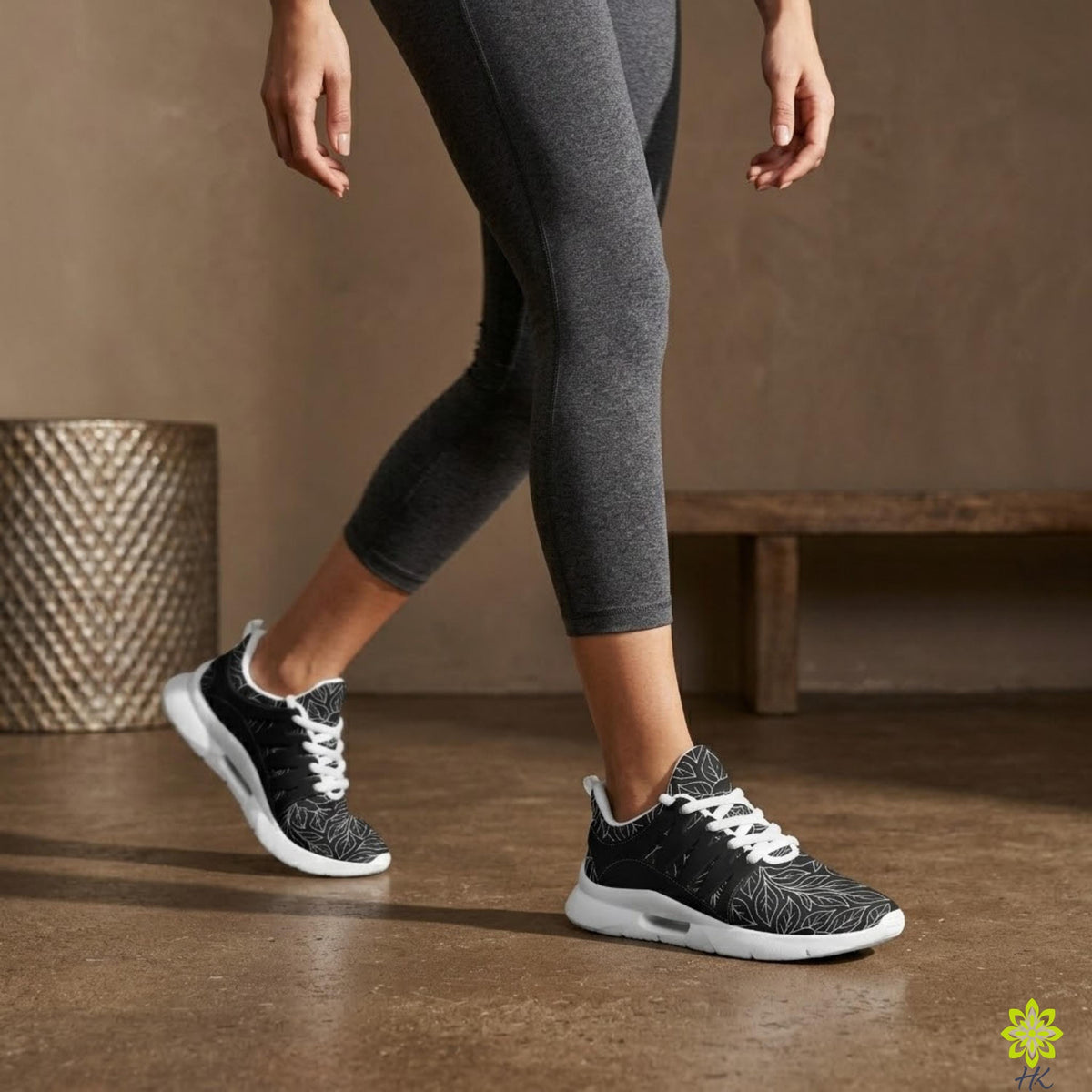 A person wearing gray leggings and black and white sneakers is walking on a concrete floor.