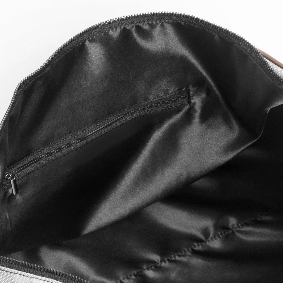 Close-up of a black leather bag with a zipper on a white background