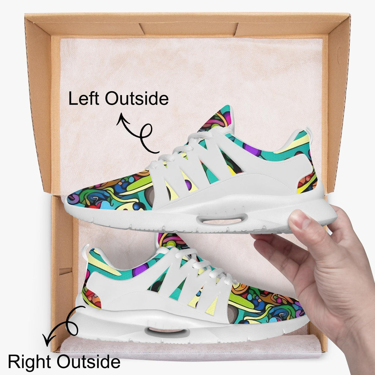 A hand is holding a pair of colorful sneakers with a patterned design, standing inside a cardboard box.