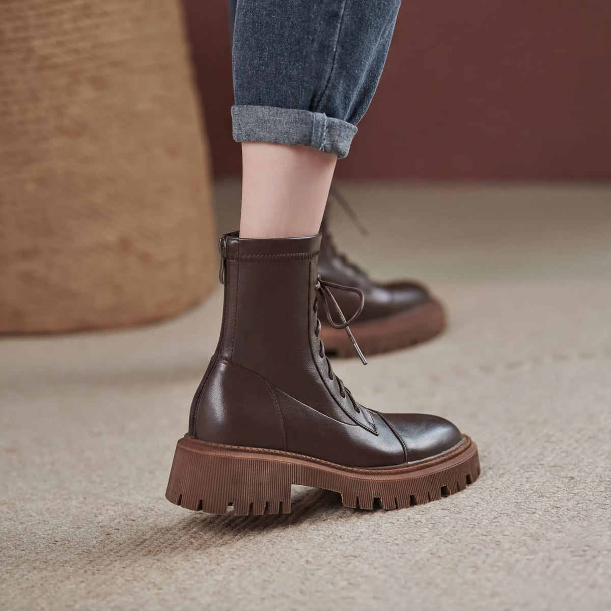 A close-up of a person's foot wearing a pair of brown leather boots with a chunky sole.